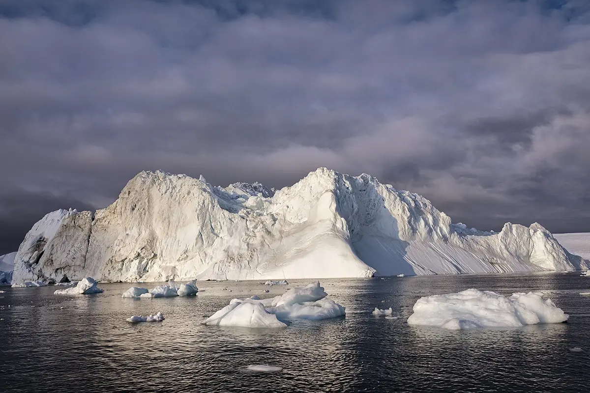 Massive iceberg in Disko Bay, Greenland, photographed with Tamron lens under dramatic Arctic skies and soft evening light