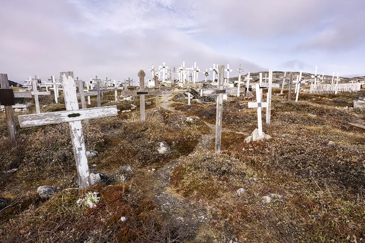 Old Ilulissat cemetery in Greenland with rows of weathered white wooden crosses photographed using a Tamron wide-angle lens