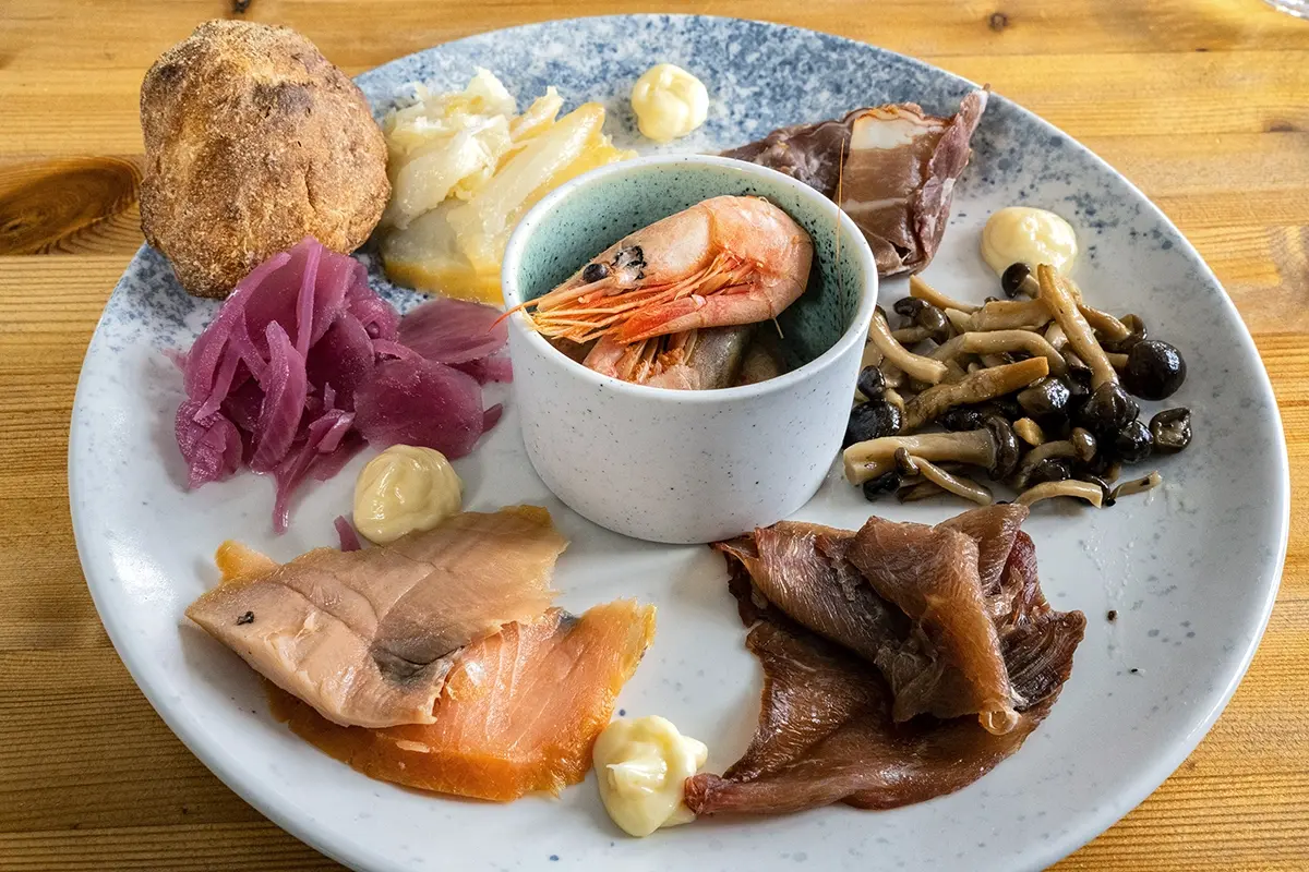 Traditional Greenlandic food platter with smoked salmon, shrimp, pickled onions, dried fish, and local specialties photographed with a Tamron lens