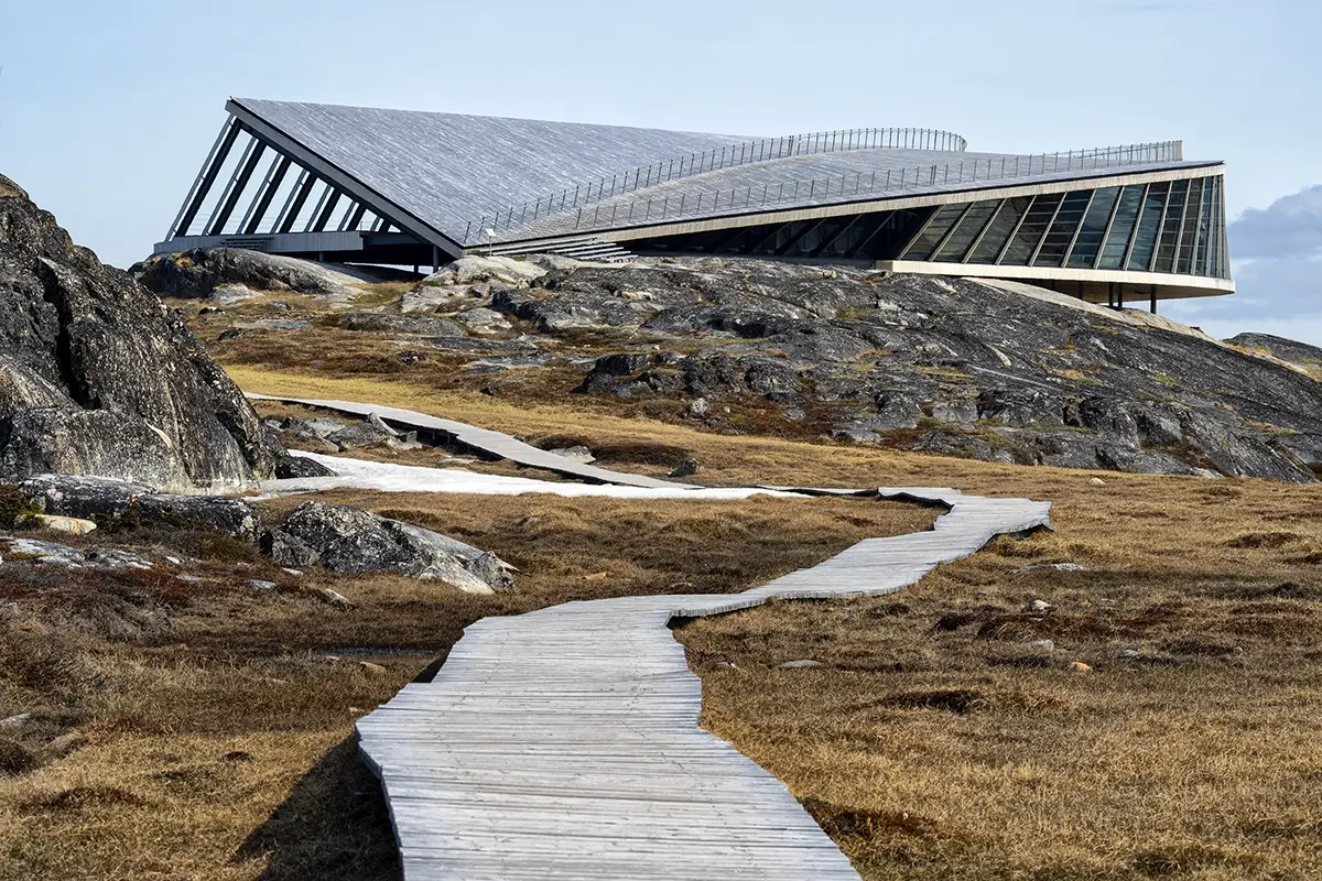 Wooden boardwalk leading to the Ilulissat Icefjord Centre in Greenland, modern architecture surrounded by Arctic tundra, photographed with a Tamron lens