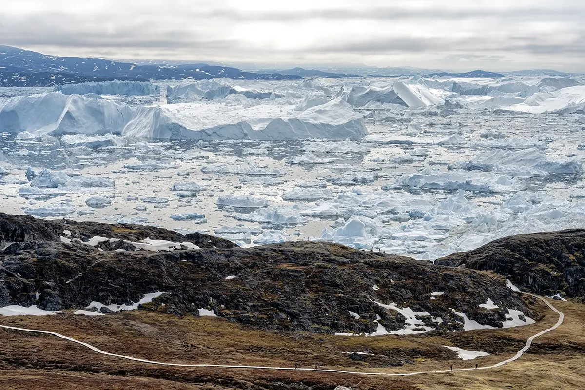 Hiking trail overlooking Ilulissat Icefjord in Greenland with panoramic view of massive icebergs and Arctic seascape, photographed with a Tamron wide-angle lens