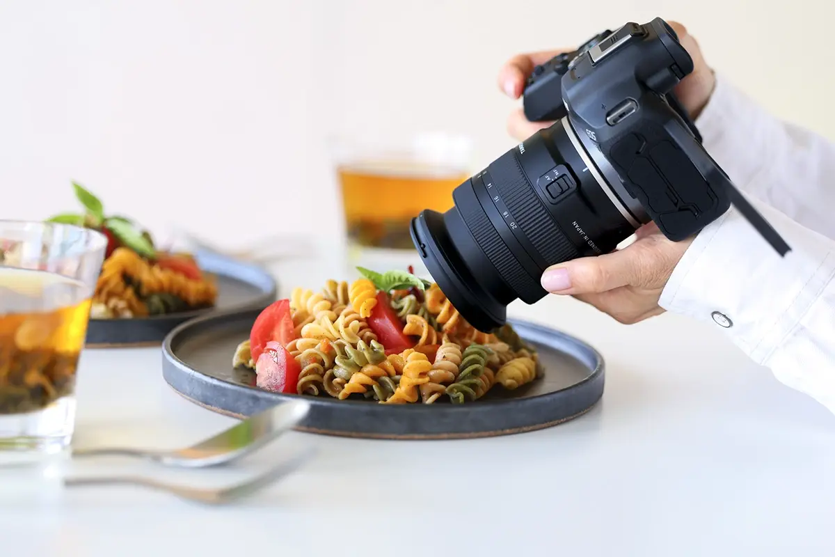 Câmera sem espelho Canon EOS com lente de montagem Tamron 11-20 mm RF fotografando um prato de massa para fotografia de alimentos.