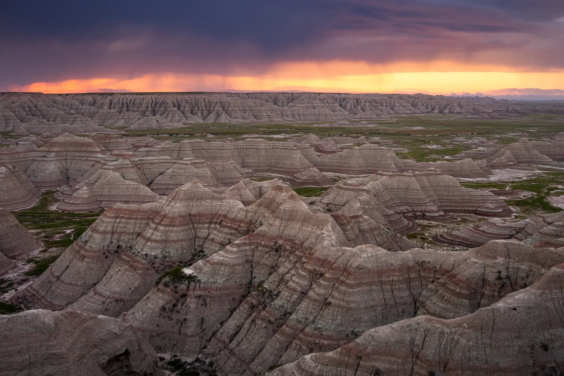 Storm clouds and sunset light over layered rock formations, capturing dramatic skies while photographing the Badlands.