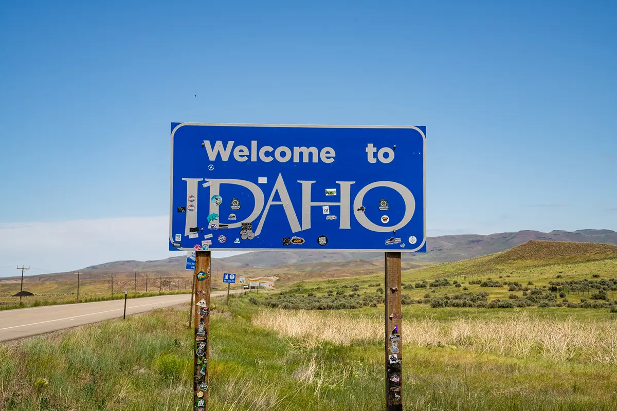 Panneau "Welcome to Idaho" sur une route panoramique, idéal pour inspirer des photos de voyage.