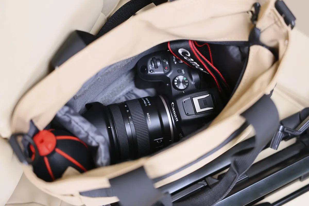 Câmera sem espelho Canon EOS R com lente de montagem Tamron 11-20 mm RF armazenada dentro de uma bolsa de câmera bege, pronta para fotografia de viagem.