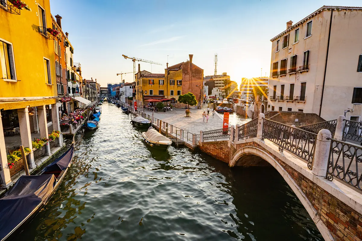 Coucher de soleil sur un canal tranquille et un pont piétonnier à Venise, en Italie, capturé pour ce guide de photographie de voyage de Venise.