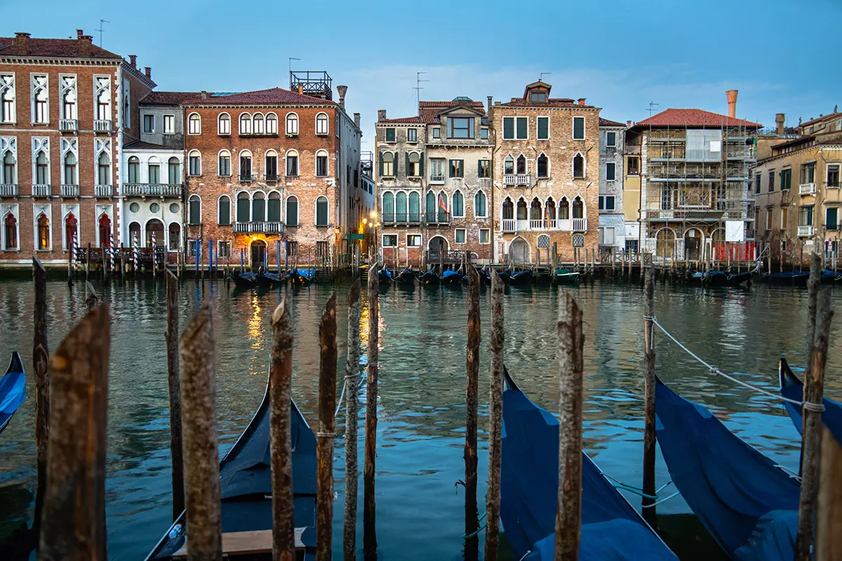 Vue matinale des gondoles attachées le long du Grand Canal avec l'architecture historique vénitienne, présentée dans ce guide de photographie de voyage de Venise.