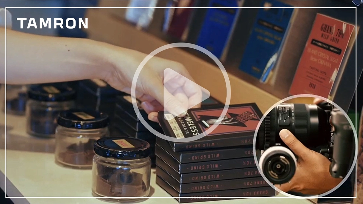 Miniatura de un vídeo de demostración de la funcionalidad A-B Focus mediante la utilidad TAMRON Lens Utility, que muestra la mano de un comprador tratando de alcanzar un chocolate y un primer plano de una cámara con un objetivo TAMRON.