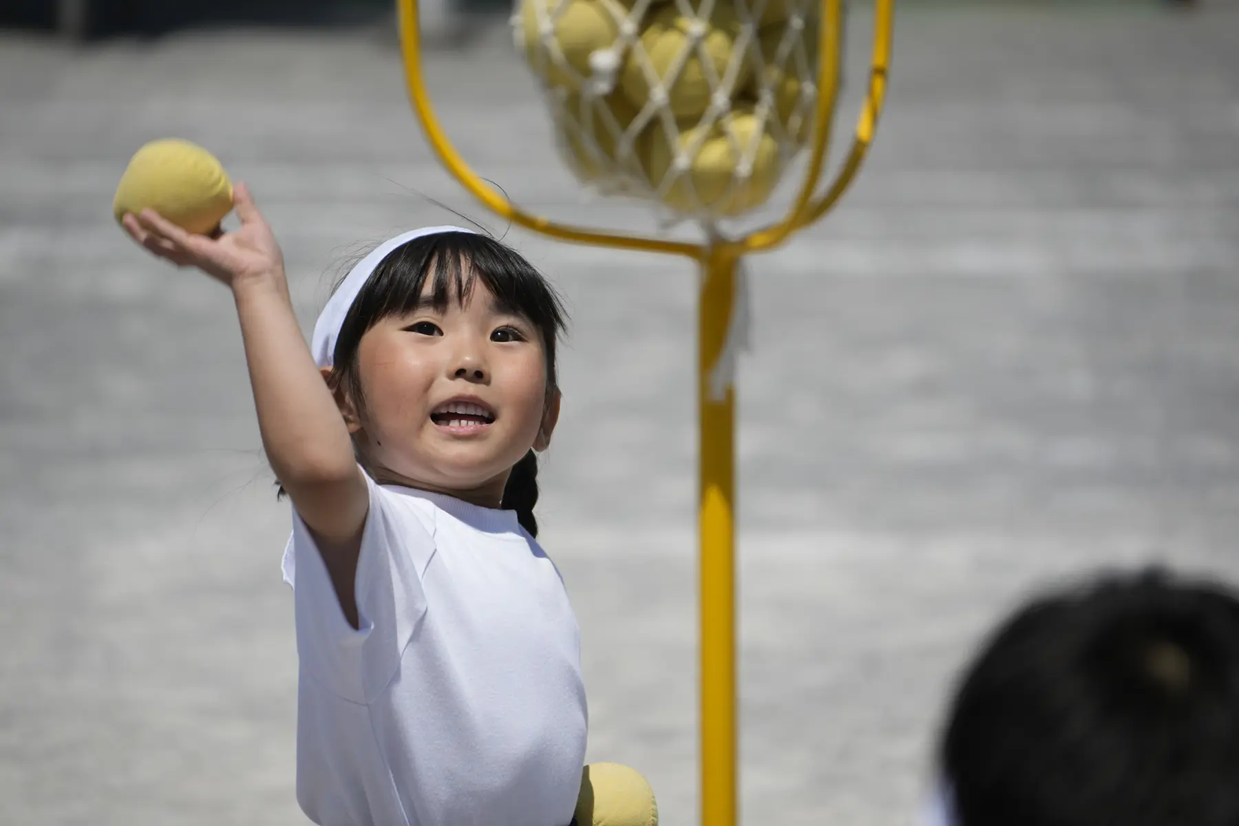 Enfant jouant au ballon lors d'un événement scolaire photographié avec un objectif tout-en-un