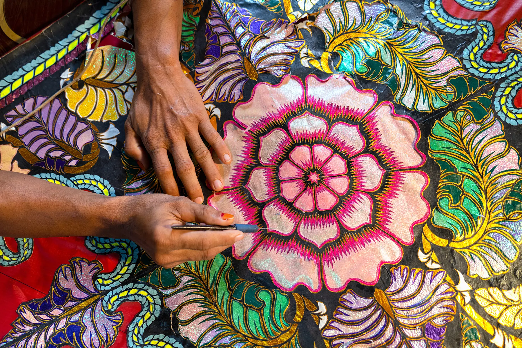 Gros plan de mains créant un motif floral coloré en tissu