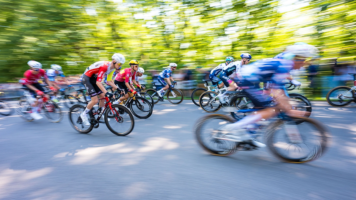 Ciclistas en movimiento durante una carrera del Gran Premio, fotografiados con el objetivo zoom gran angular Tamron 16-30 mm F/2,8 Di III VXD G2, capturando la velocidad y la energía con un desenfoque de movimiento creativo.