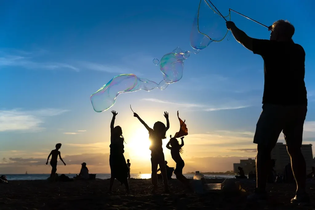 Children playing with bubbles at sunset on the beach, captured in the Tamron brand story