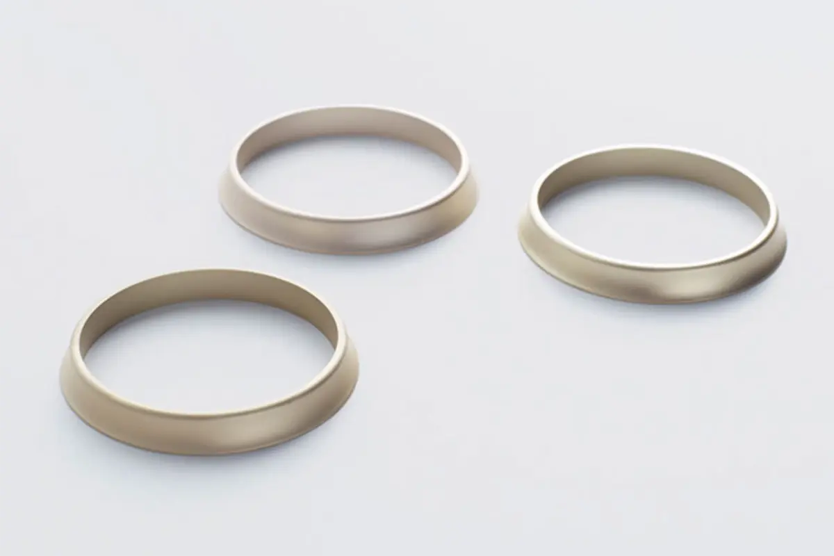 Three Tamron brand rings on a table. Tamron designed the ring around the concept of relationship, connecting the lens to the camera.