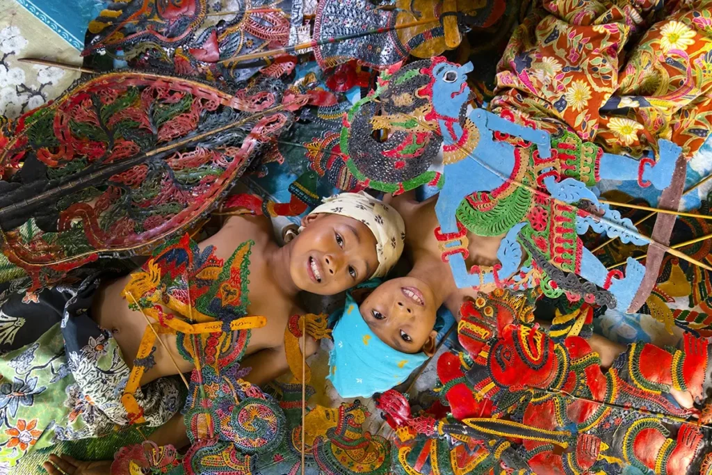 Children smiling among colorful shadow puppets, reflecting cultural storytelling in the Tamron brand story.
