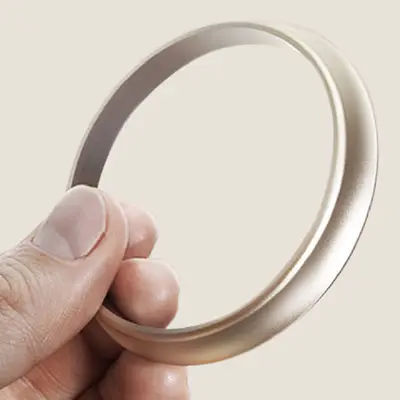 Hand holding a Tamron lens brand ring, Tamron’s symbol of commitment to its users.