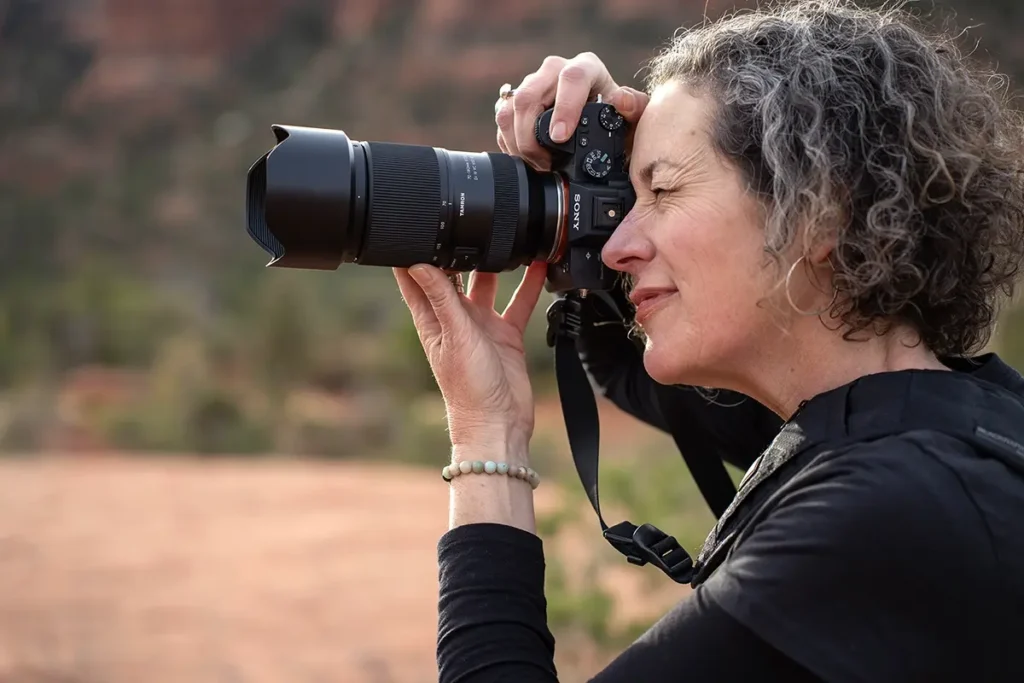 Photographer using a Sony camera with Tamron lens outdoors, part of the Tamron brand story