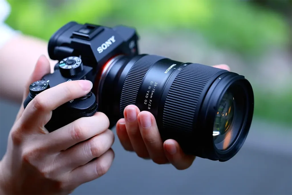 Hands holding a Sony camera with Tamron 28-75mm F/2.8 lens, featured in the Tamron brand story.