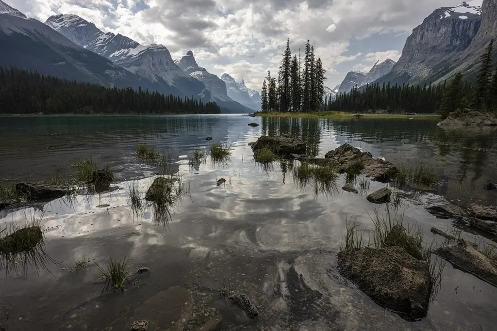 Wide-angle landscape photo of Spirit Island at Maligne Lake in Jasper National Park, Canada, captured with a Tamron trinity lens, showing mountains, pine trees, and reflections on the water.