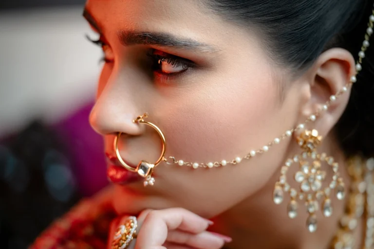 Uma mulher usando um conjunto de joias de noiva tradicional indiana, com foco em seu anel de nariz e brinco ornamentados.