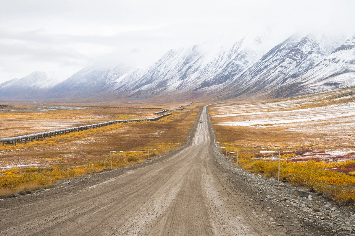 Dalton Highway menant vers la chaîne de Brooks couverte de neige pendant les couleurs d'automne de l'Alaska - une scène emblématique de la photographie de paysage de l'Alaska en automne.