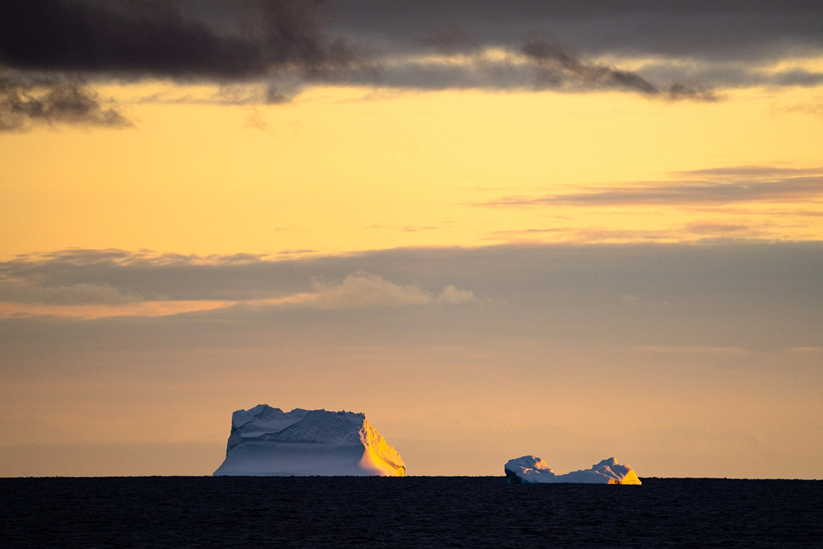 Icebergs glowing at sunset on the Southern Ocean during an Antarctica cruise photography expedition.