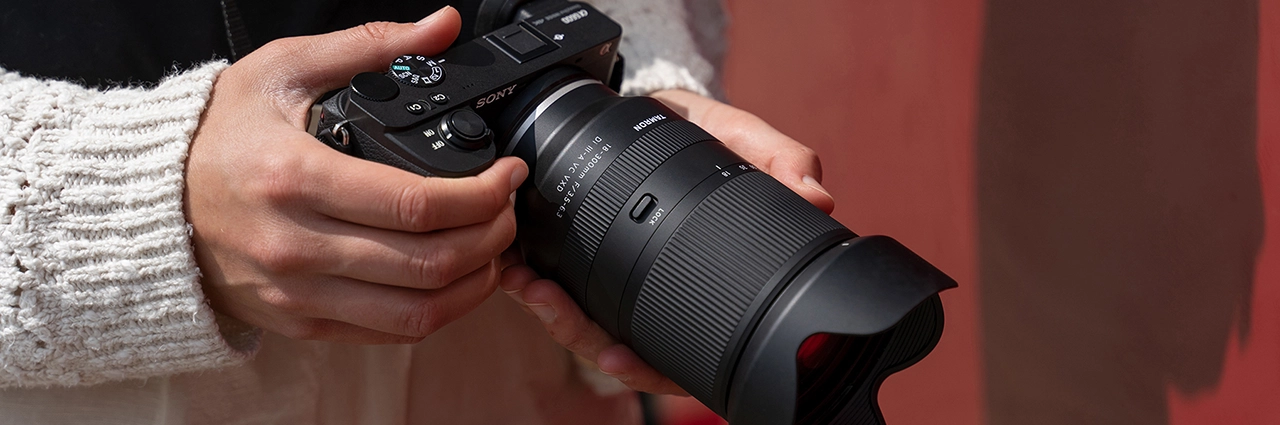 Persona que sostiene una cámara sin espejo Sony APS-C con un objetivo Tamron 18-300mm F3.5-6.3.