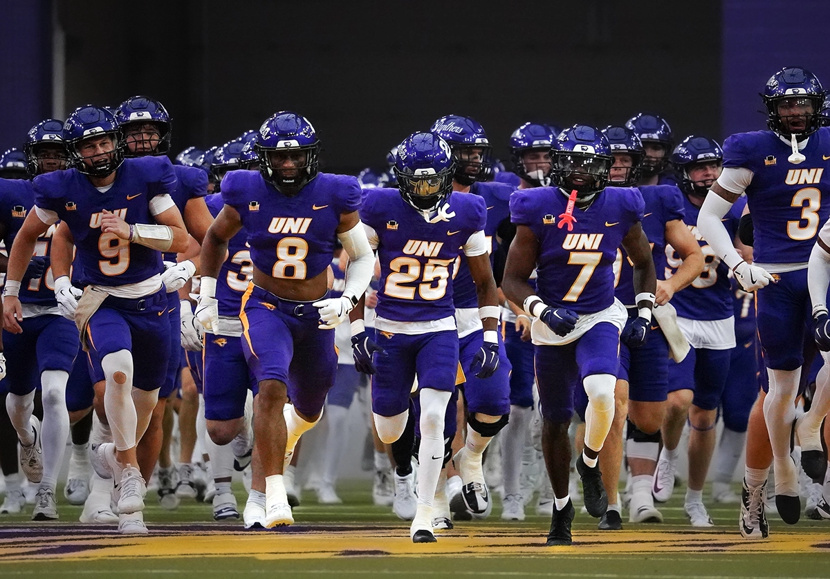 A team of football players running out on the field before the game.