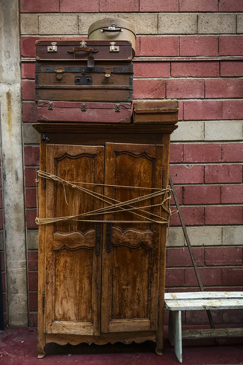 Valises et cartons à chapeaux empilés sur une vieille armoire usée par les intempéries