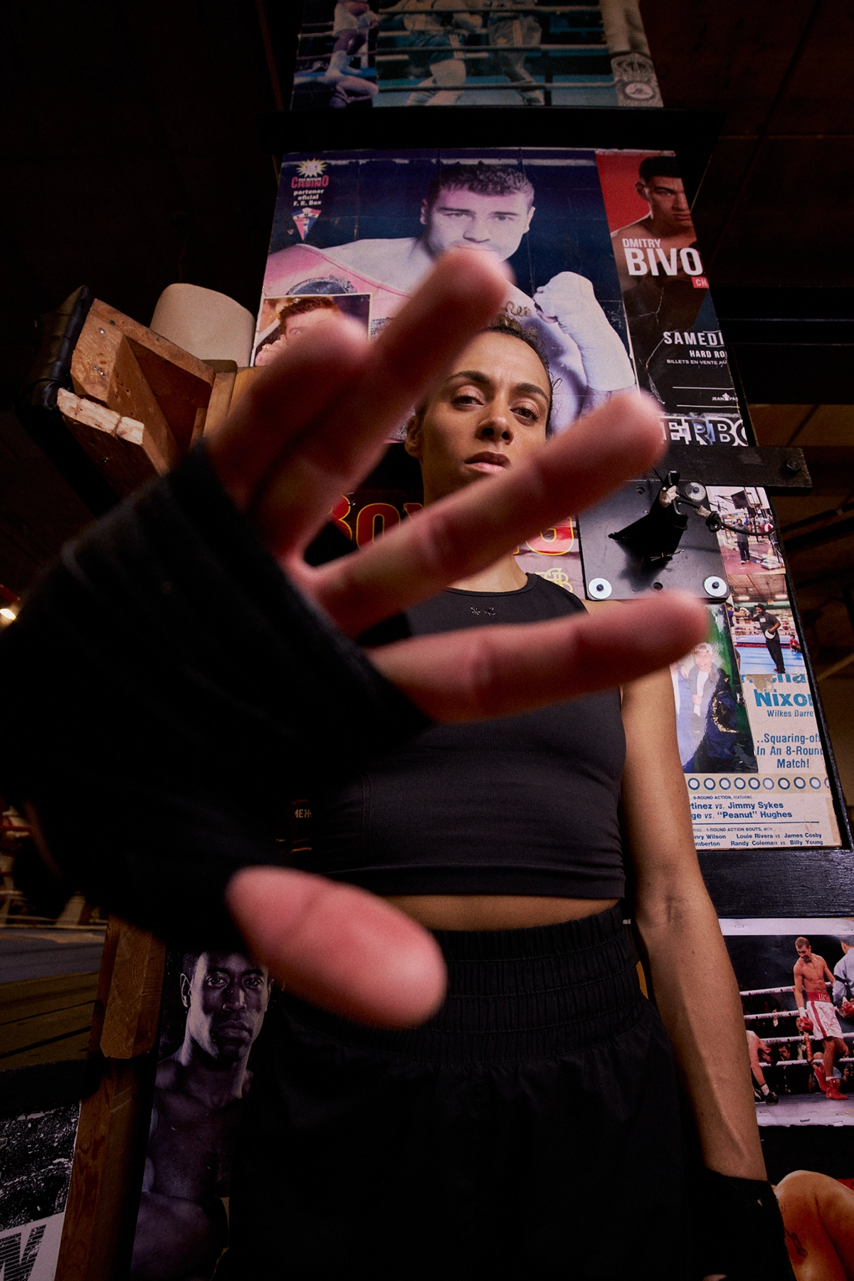 Low-angle portrait of a boxer reaching toward the camera with posters in the background, showcasing creative perspective and storytelling.