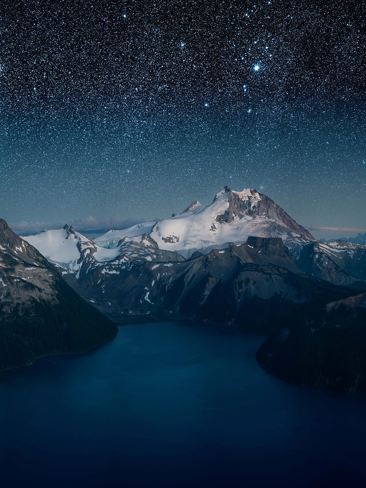 Starry night sky over snow-covered mountains in British Columbia, captured with the Tamron 90mm F/2.8 Di III VXD Macro lens, showing its capability for astrophotography beyond outdoor macro photography.