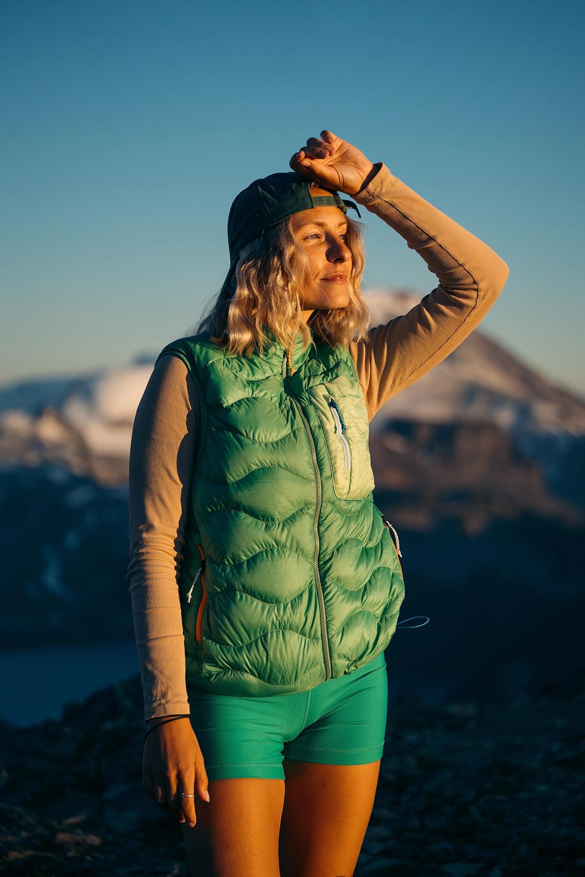 Woman in green hiking gear photographed at golden hour with the Tamron 90mm F/2.8 Di III VXD Macro lens, demonstrating its versatility beyond outdoor macro photography.