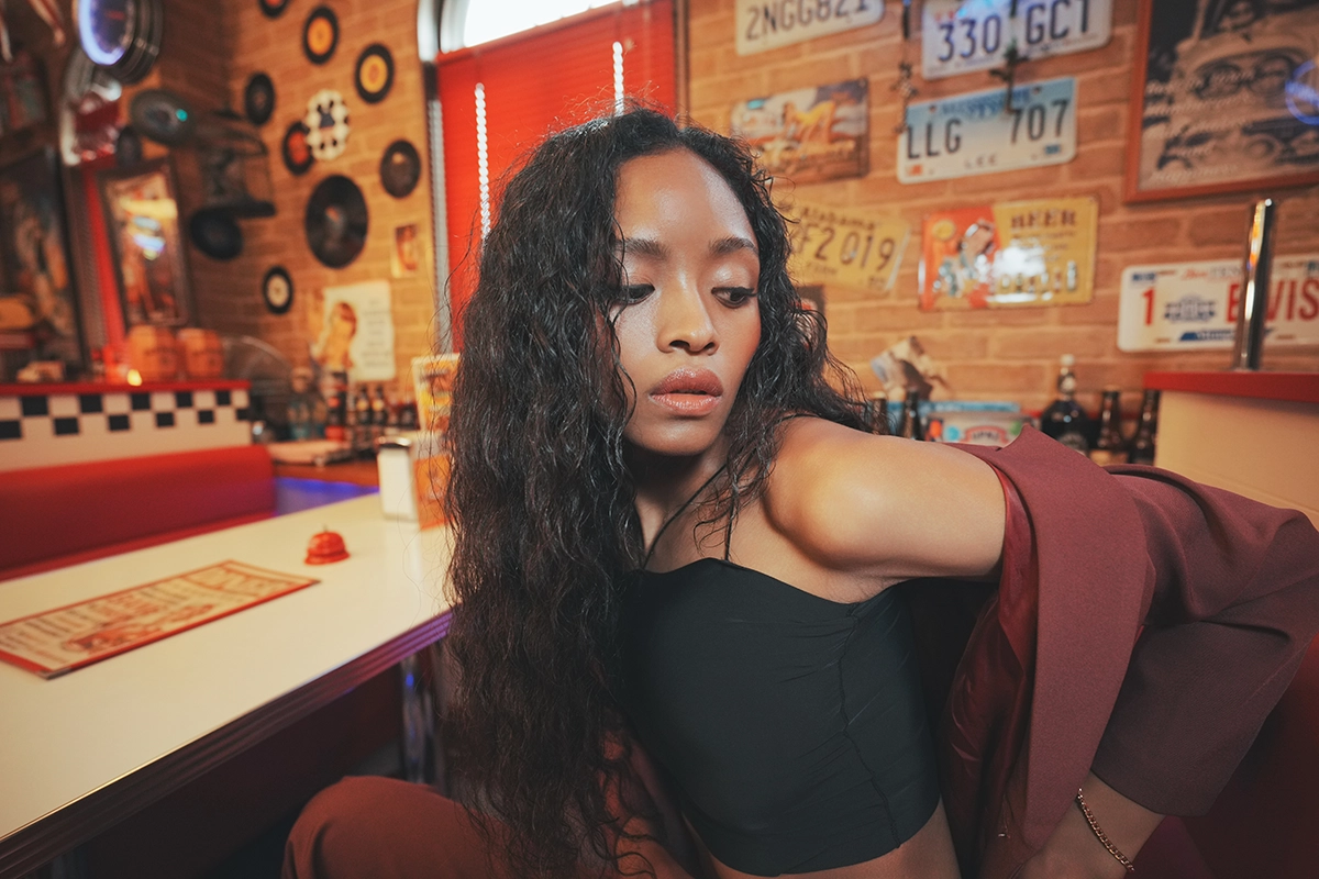 Portrait d'une femme dans un restaurant rétro avec des éléments d'arrière-plan détaillés, montrant plus d'informations sur l'arrière-plan dans la composition.