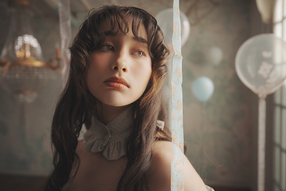 Retrato en primer plano de una joven bajo una suave luz interior, capturado en formato de imagen RAW para obtener tonos de piel naturales y detalles finos.