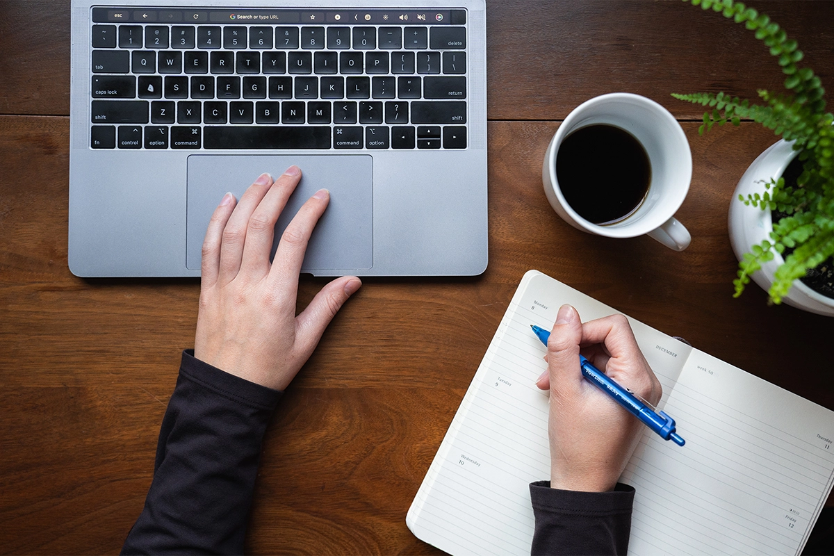 Vue aérienne d'une personne prenant des notes à côté d'un ordinateur portable et d'une tasse de café, illustrant le processus de narration visuelle pour les photographes.