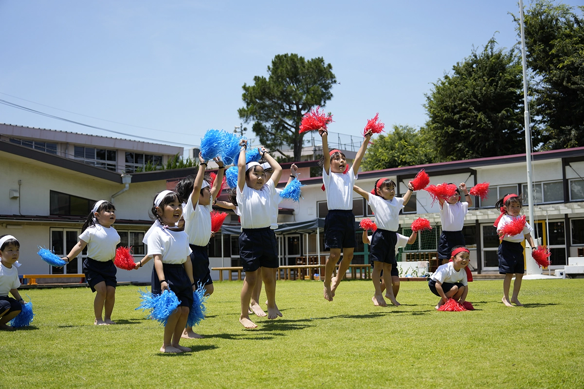 Des enfants exécutant une chorégraphie lors d'une journée sportive à l'école primaire, photographiés avec une vitesse d'obturation rapide afin de figer le mouvement de saut et l'action lumineuse en extérieur.