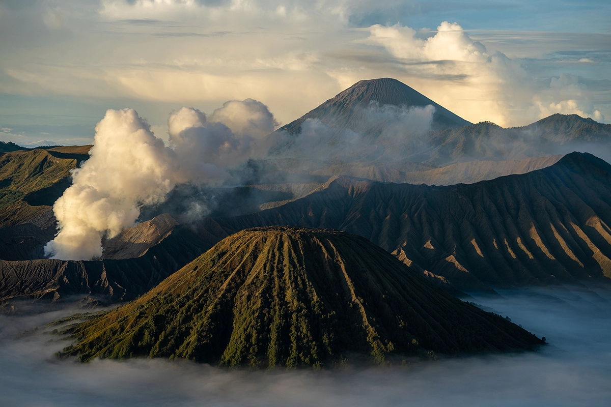 Layered volcanic peaks and drifting clouds in the Bromo volcano complex, Indonesia, photographed during travel landscape photography with the Tamron 70-180mm F2.8 G2 lens.