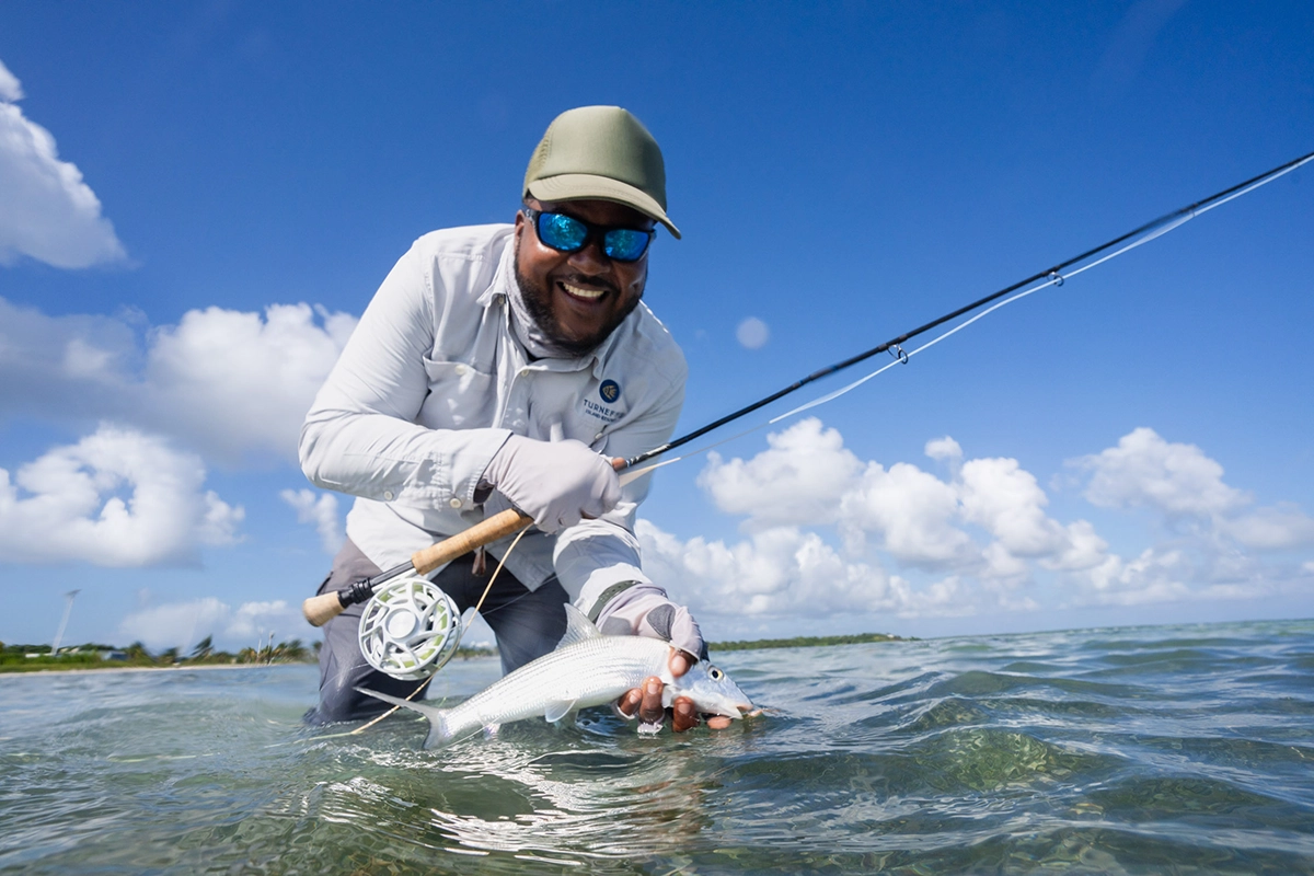 Pescador mostrando un pez ratón tras una exitosa jornada de pesca con mosca en el atolón Turneffe.