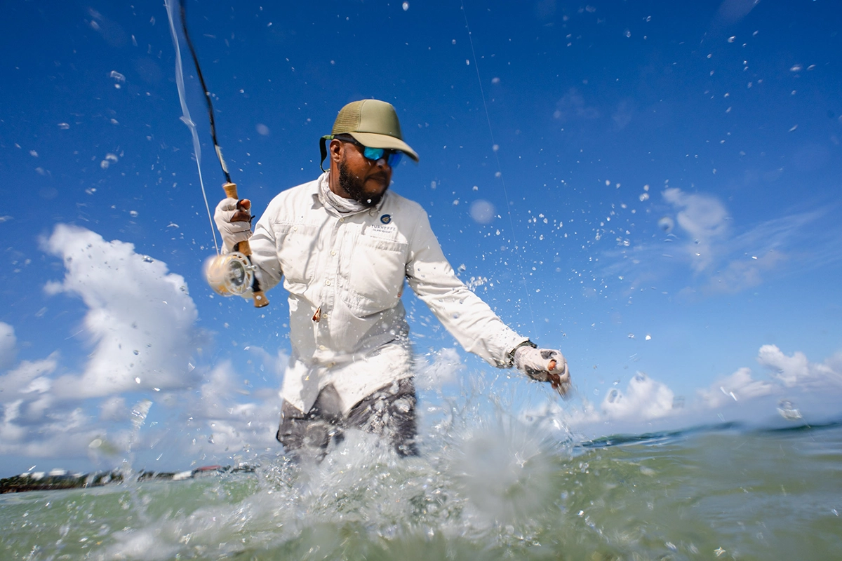 Pescador con mosca luchando contra un pez con salpicaduras de agua espectaculares.