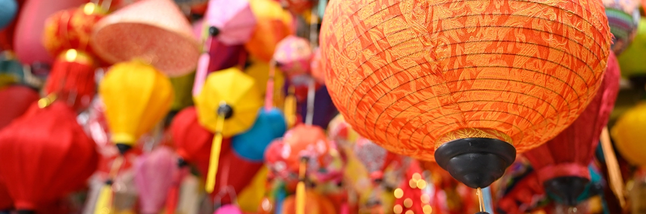 Lanternas coloridas penduradas em um mercado vietnamita, com uma lanterna laranja brilhante em foco nítido, fotografada com a Tamron 28-75 mm F2.8 G2.