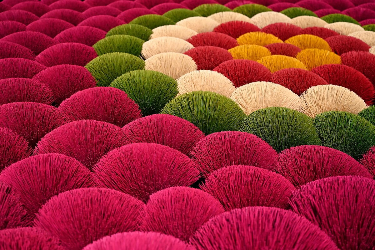 Feixes coloridos de palitos de incenso dispostos em padrões sobrepostos em uma oficina vietnamita, fotografados com a Tamron 28-75mm F2.8 G2.