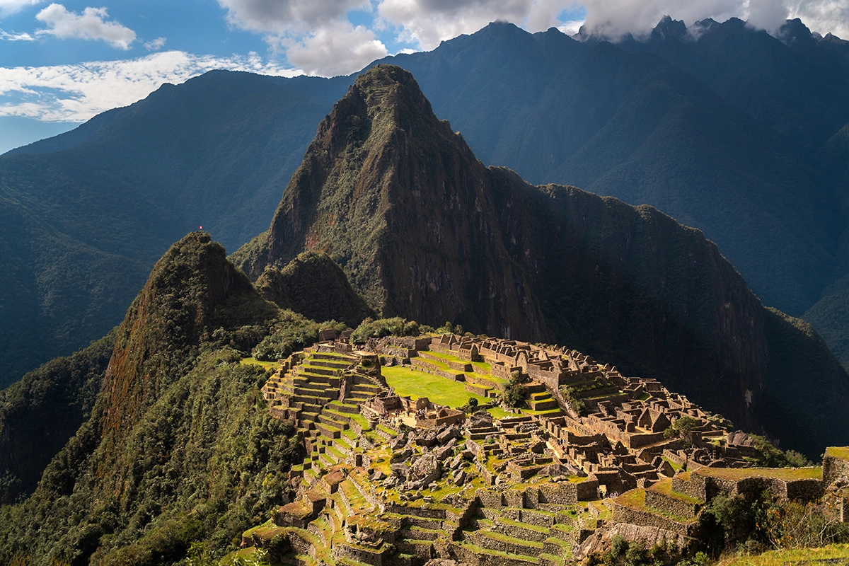 Fotografia de paisagem de Machu Picchu capturada com a lente Tamron 35-150 mm F2-2.8, mostrando ruínas detalhadas em primeiro plano e camadas dramáticas de montanhas ao fundo.