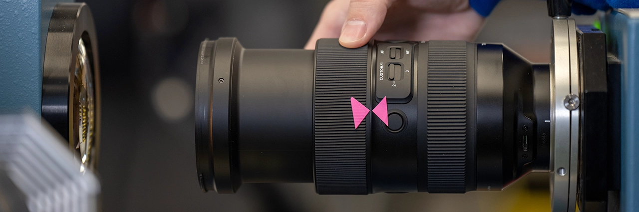 Tamron lens undergoing authorized factory calibration during professional repair service.