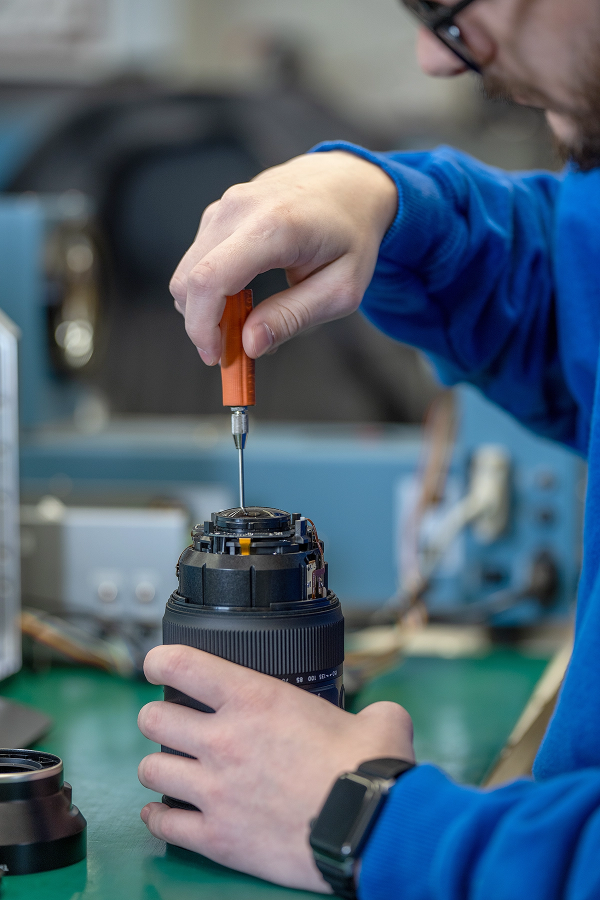 Tamron technician performing an authorized lens repair using original factory components.