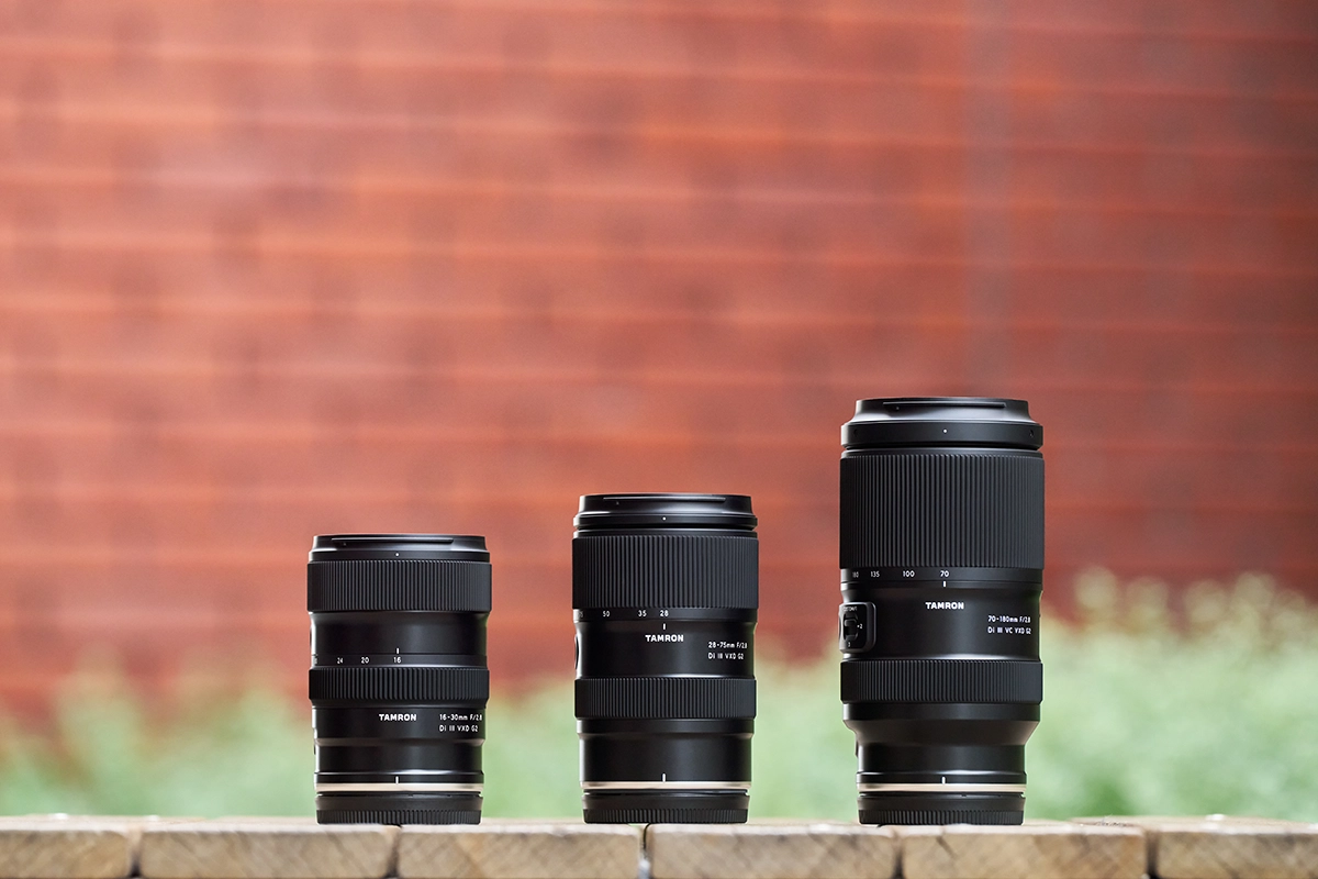 Três lentes zoom Tamron de diferentes faixas de distância focal dispostas lado a lado, ilustrando como a escolha da distância focal afeta o tamanho, o alcance e o estilo de fotografia.