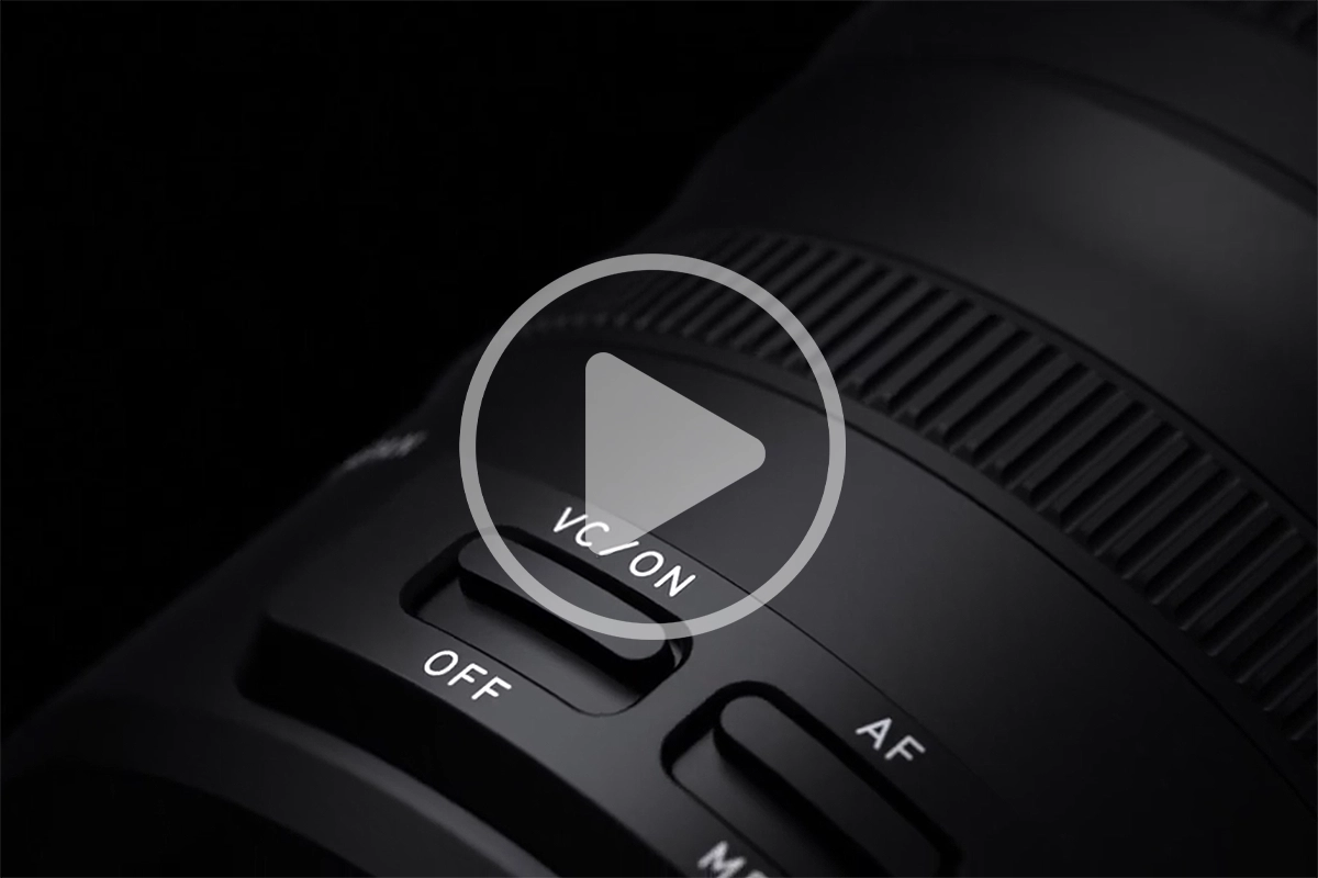 Close-up of a Tamron lens showing the VC vibration compensation switch for optical image stabilization.