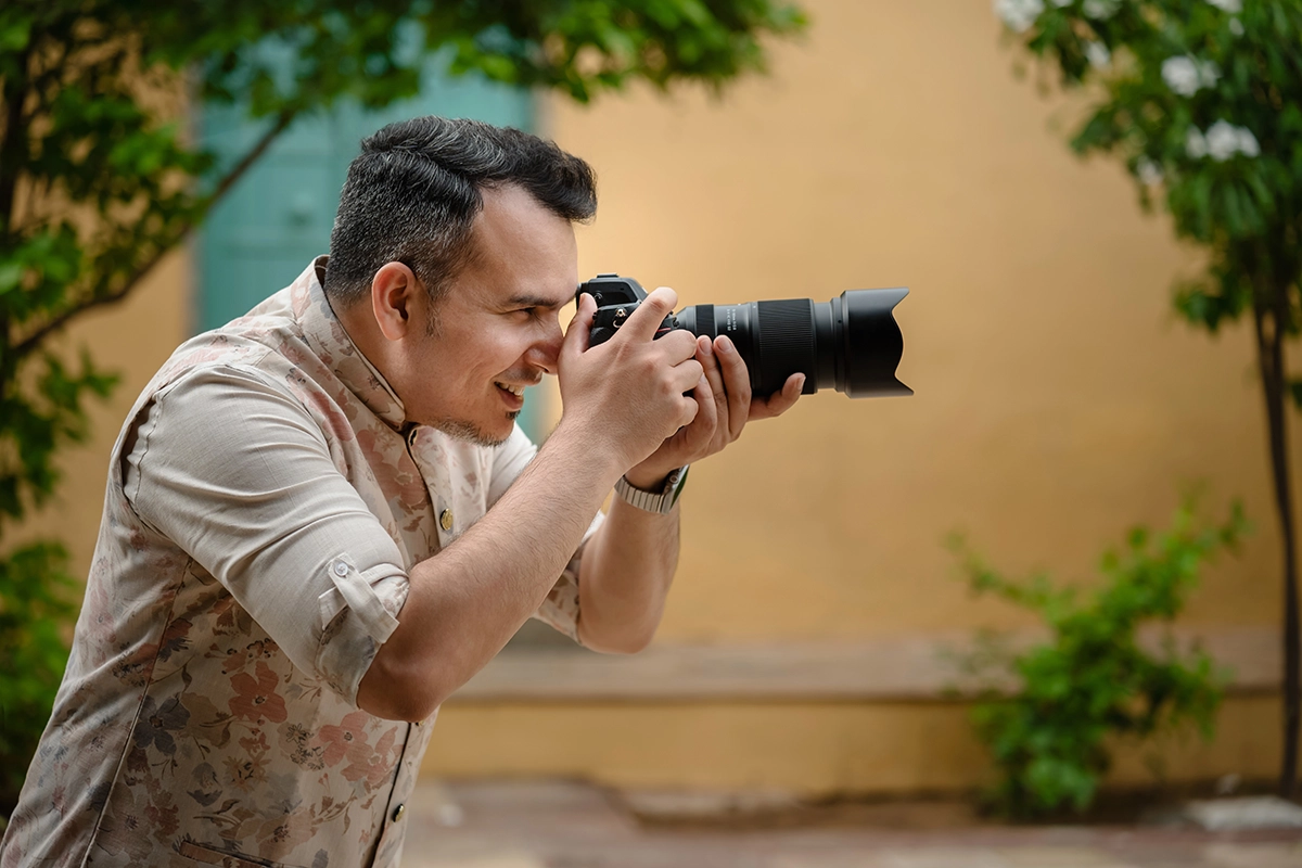 Photographer shooting handheld with a Tamron lens featuring vibration compensation.