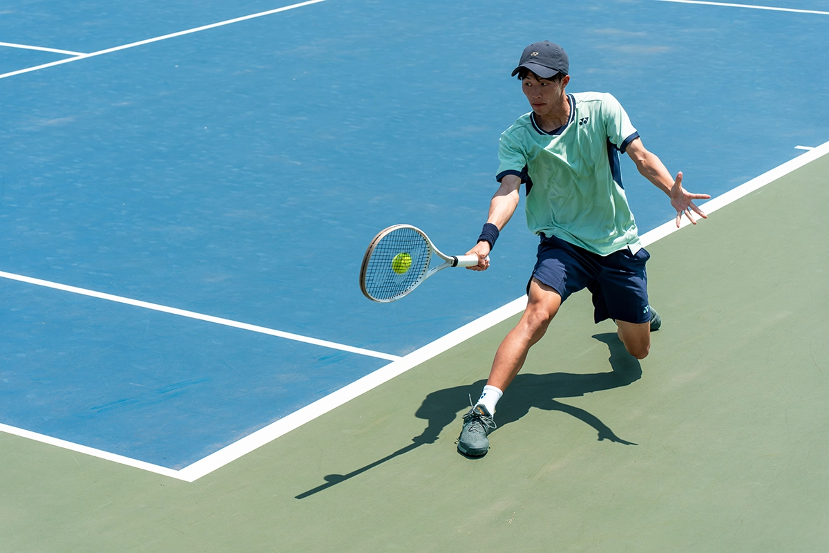 Joueur de tennis capturé à mi-course avec une vitesse d'obturation rapide pour figer l'action et démontrer le contrôle du mouvement en photographie de sport.