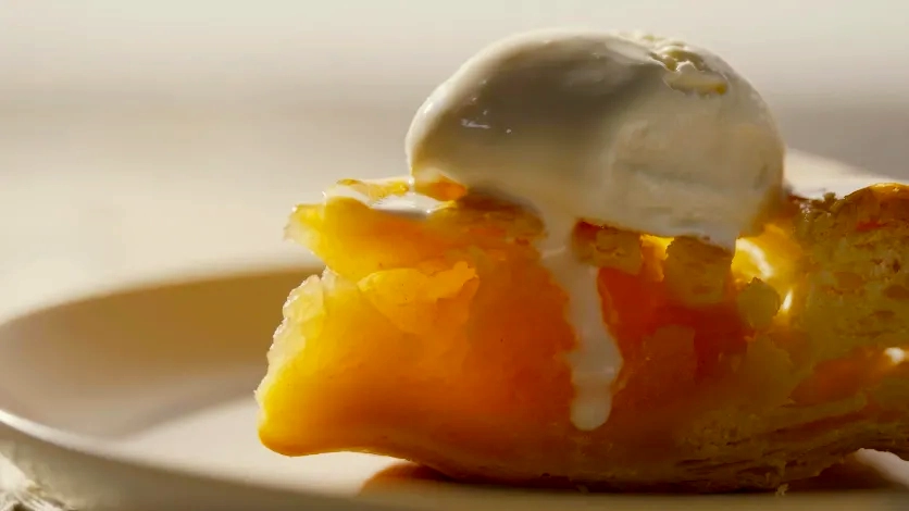Close-up of apple pie with melting ice cream to highlight texture, warmth, and a cinematic shallow depth of field.