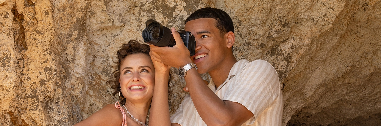 Photographer using a camera and lens outdoors, representing lens choice for different types of photography.