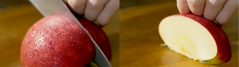 Close-up of a red apple being sliced, with a freshly cut apple half on a wooden surface.